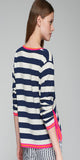 Blue and white striped sweater. V-neck. Contrasts in sleeves and collar in pink and orange. Side slits closed with gold metal buttons.

100%WOOL
